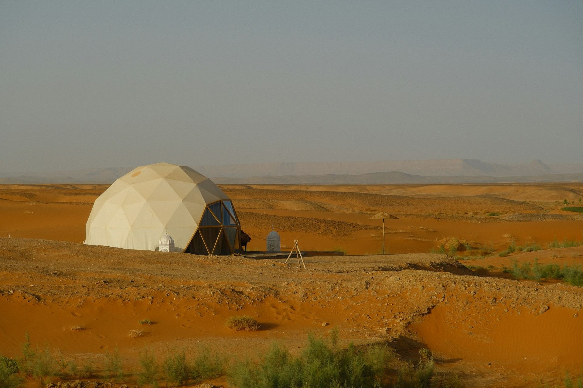 Geodesic glamping dome standing in an open desert landscape